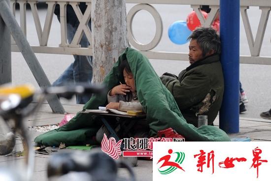 小女孩随父亲街头乞讨寒风中裹棉被写作业