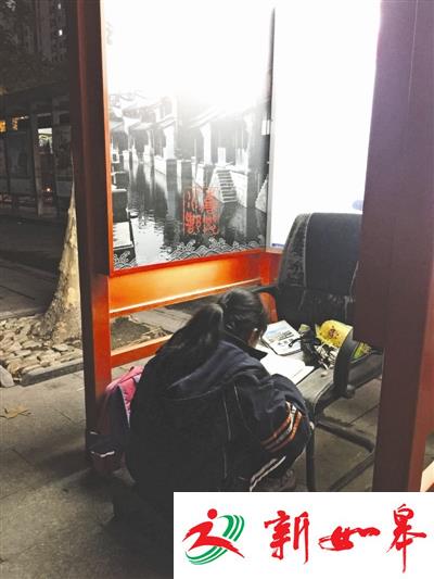 12岁女孩陈晓华在电话亭内借着灯光做作业 图据钱江晚报