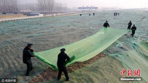 12月16日，北京大兴区城管队员正在苫盖建筑垃圾。图片来源：视觉中国