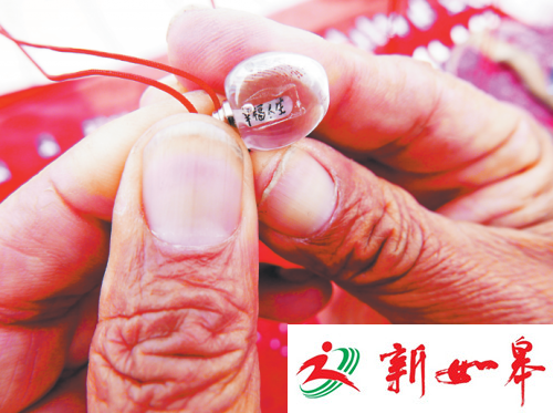 孙传富在大米上刻完字后，将大米装在琉璃饰品里。